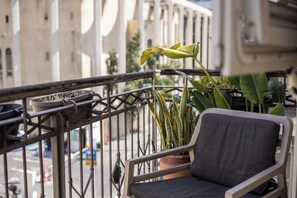 A balcony with a chair, potted plants, and a railing.