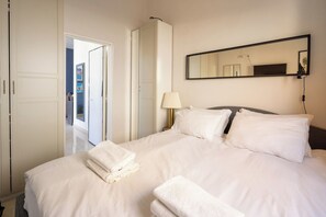 A hotel room with a bed, a mirror, and a door leading to another room.