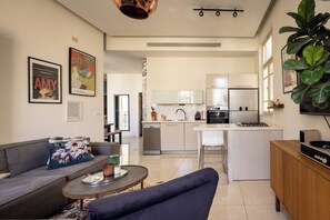 A modern living room with a sofa, a coffee table, and a kitchen in the background.
