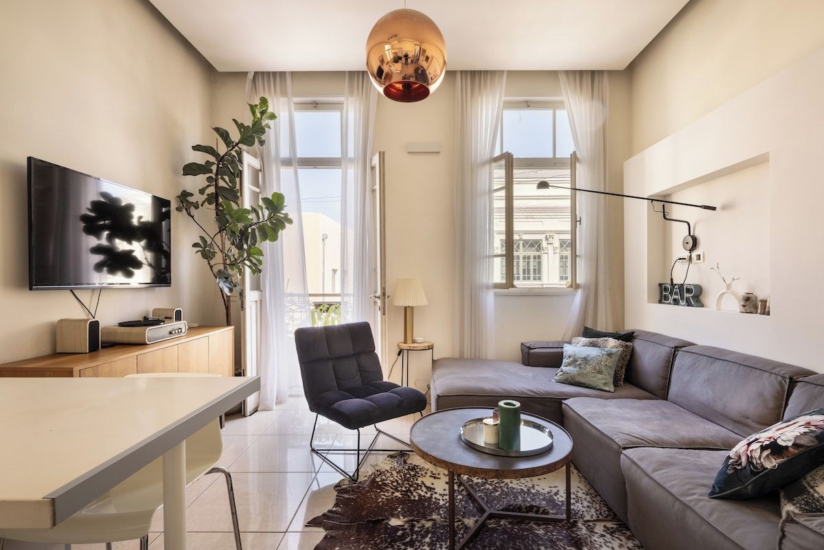 A modern living room with a flat-screen TV, a sofa, a dining table, and a coffee table.
