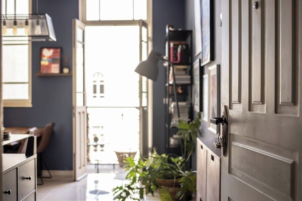 A hallway with a wooden door, a desk, a chair, and a bookshelf.