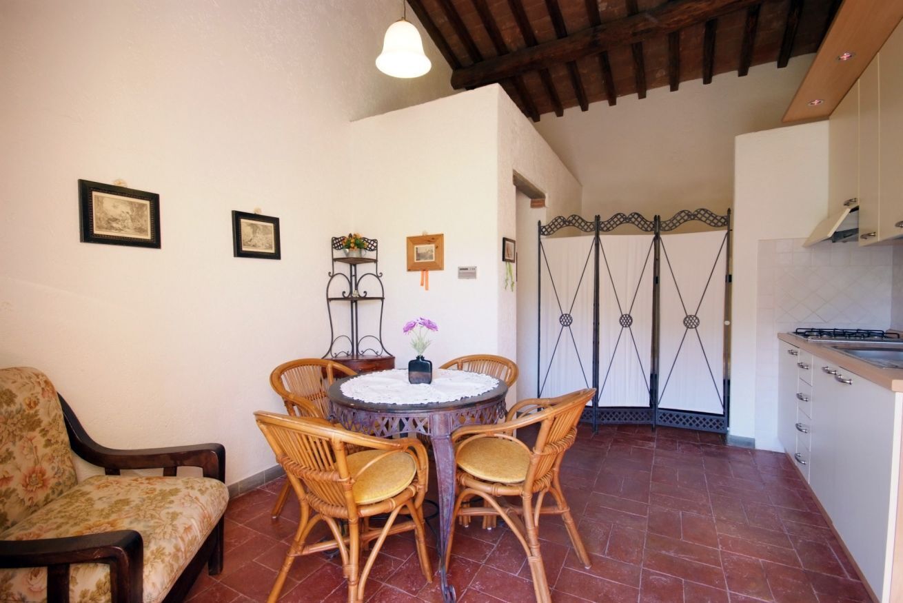 A dining area with wicker chairs, a round table, and a vase of flowers.