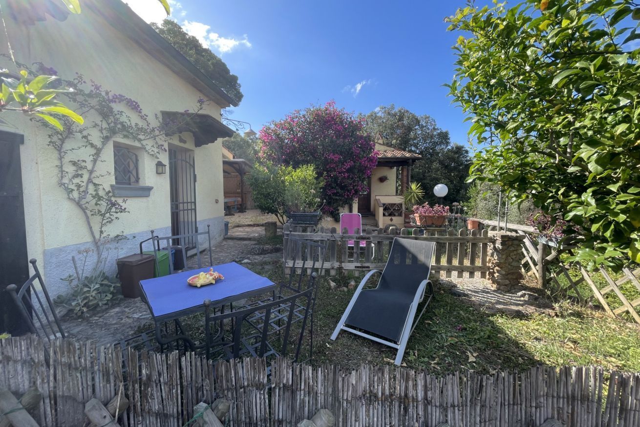 A patio with a table and chairs, a wooden fence, and a house with a tiled roof.