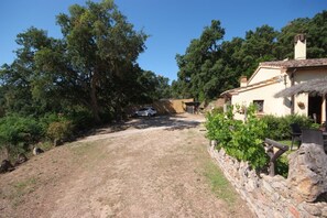 Une propriété rurale avec un chemin de terre, des murs en pierre et un bâtiment doté d’un toit de chaume.