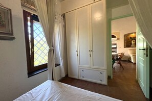Een slaapkamer met een bed, een kledingkast en een raam met gordijnen.