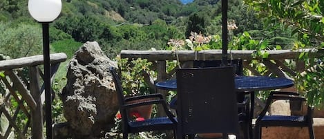 Un espacio al aire libre con mesas y sillas, un farol y vistas a un paisaje montañoso.