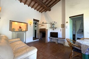 Una sala de estar con chimenea, televisor, sofá y comedor con mesa y sillas.