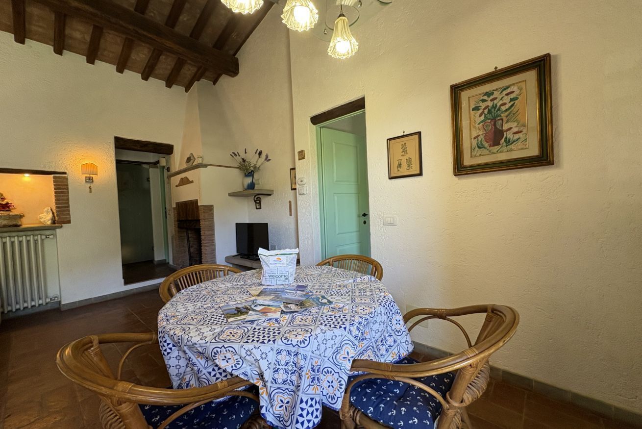 Un coin repas avec une table ronde, des chaises en osier et une nappe à motifs.