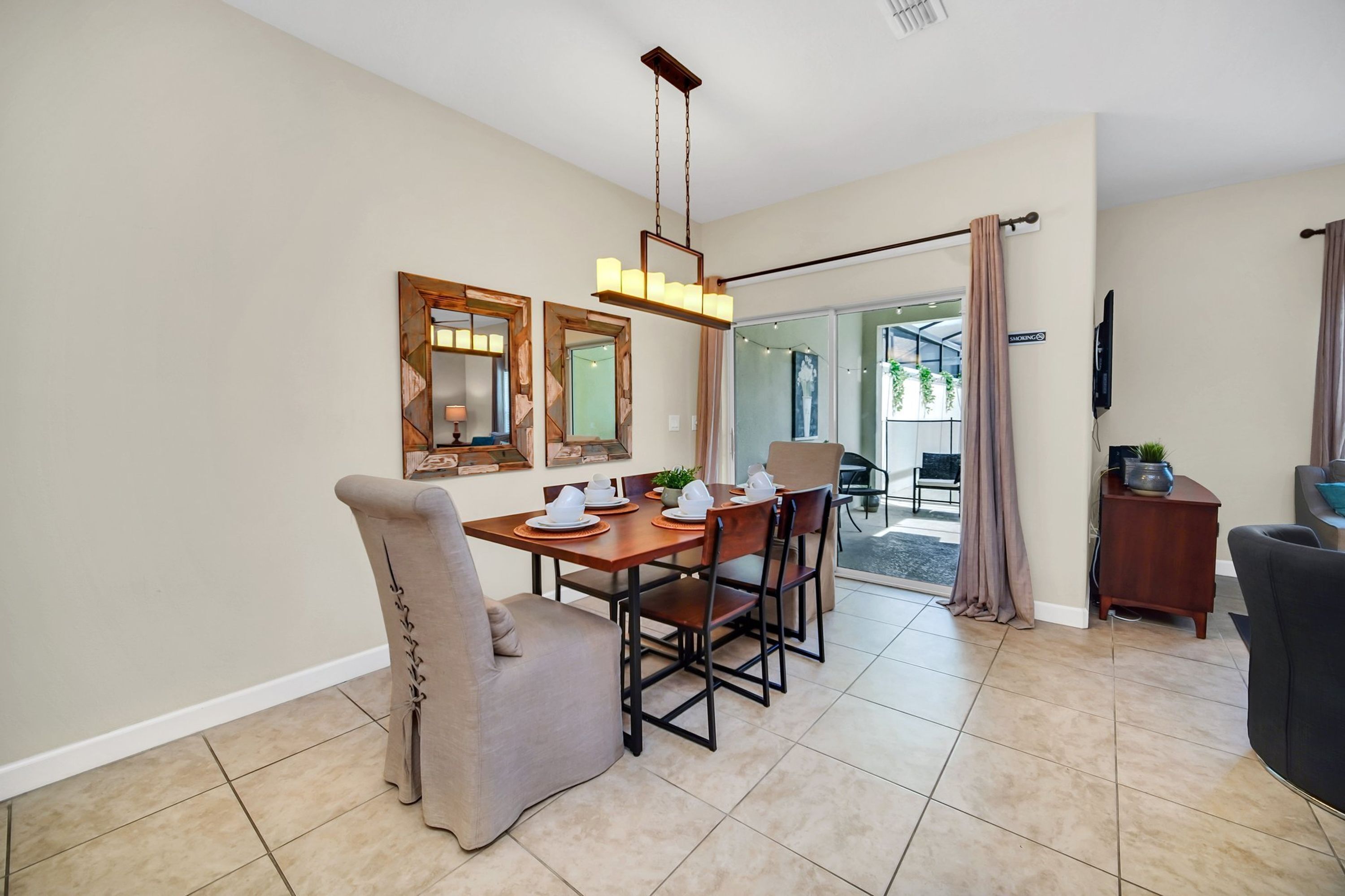 A dining area with a wooden table set for four, surrounded by chairs, and a chandelier above.