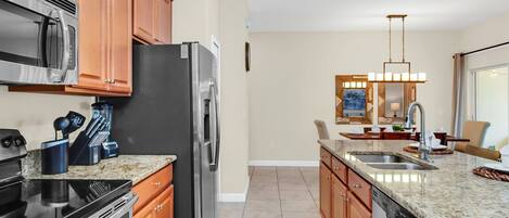 A modern kitchen with granite countertops, stainless steel appliances, and wooden cabinets.