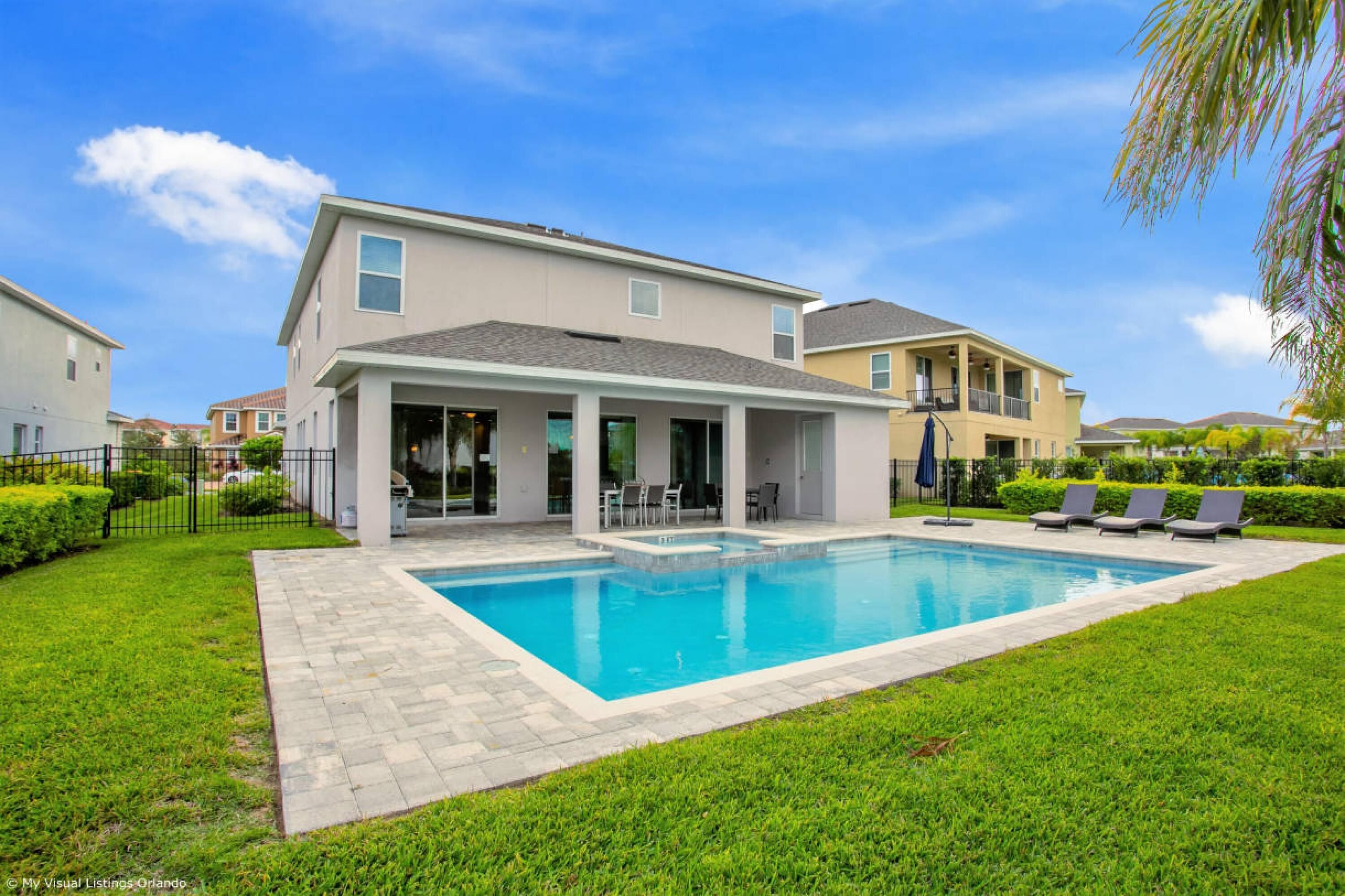 A modern two-story house with a swimming pool, covered patio, and a well-maintained lawn.