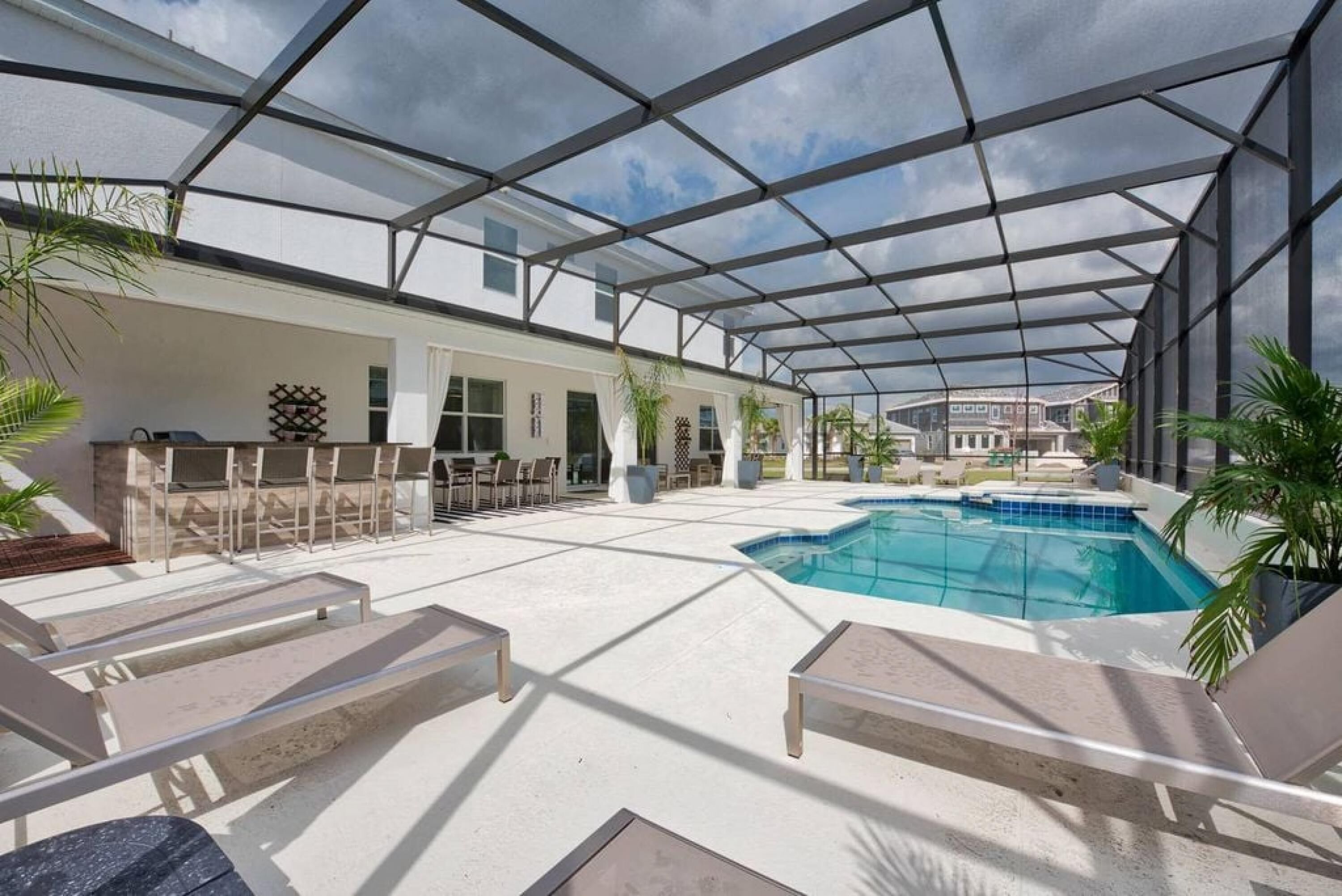 Un área de piscina exterior techada con sillones de descanso, zona de barbacoa y vistas de los edificios circundantes.