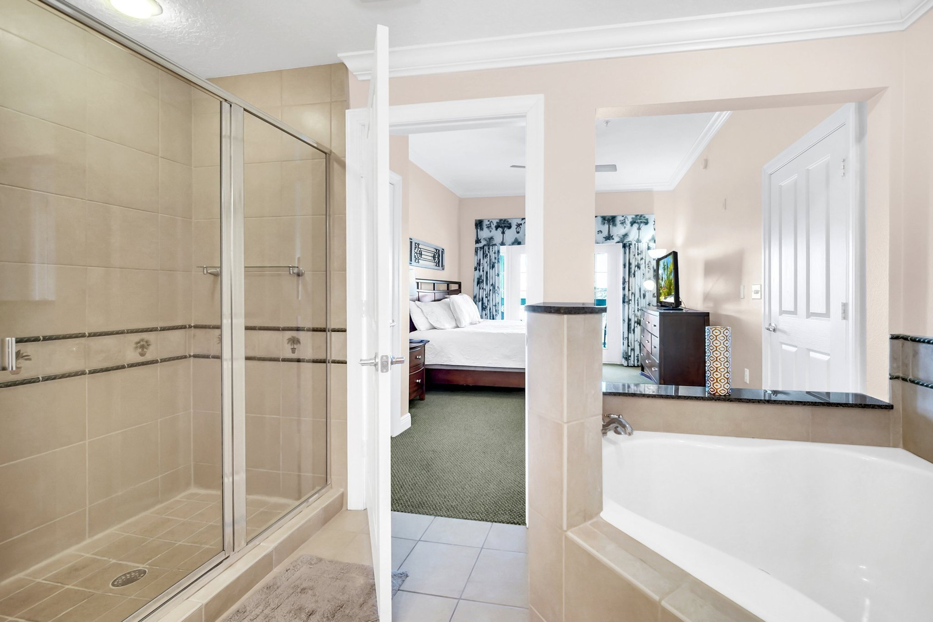 Une salle de bain moderne dotée d’une douche à parois de verre, d’une baignoire et d’une chambre à coucher ouverte, avec un lit et une table de chevet.