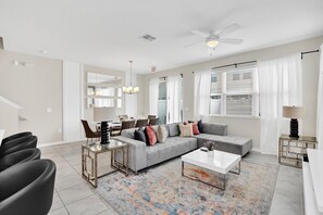 A modern living room with a grey sofa, black chairs, a coffee table, and a patterned rug. - Comfy House at Compass Bay Cb102 (Kissimmee)