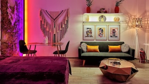 Uma sala de estar moderna com um sofá, uma mesa de centro, uma mesa de jantar com cadeiras e uma parede com obras de arte emolduradas.