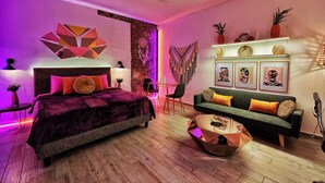 Quarto moderno com cama, sofá verde e mesa de centro.