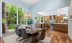 A modern kitchen with wooden cabinets, a central island, and a dining area with a table set for six. - Wilton Manors Stunning Gated Oasis (Fort Lauderdale)