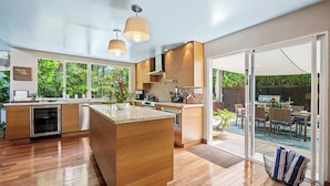 Een moderne keuken met houten keukenkastjes, een centraal eiland en grote ramen.