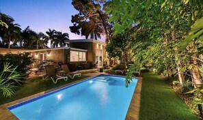 A swimming pool with lounge chairs and a small building with a balcony. - Wilton Manors Stunning Gated Oasis (Fort Lauderdale)