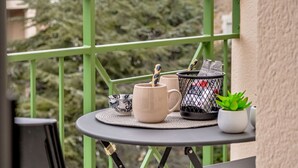 A balcony with a small table, two chairs, a potted plant, and a coffee maker. - Le Manon by Interhome (Dinard)