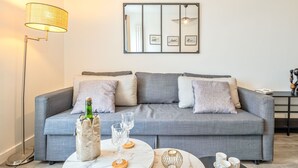 A modern living room with a grey sofa, a floor lamp, a coffee table, and a framed artwork on the wall. - Le Manon by Interhome (Dinard)
