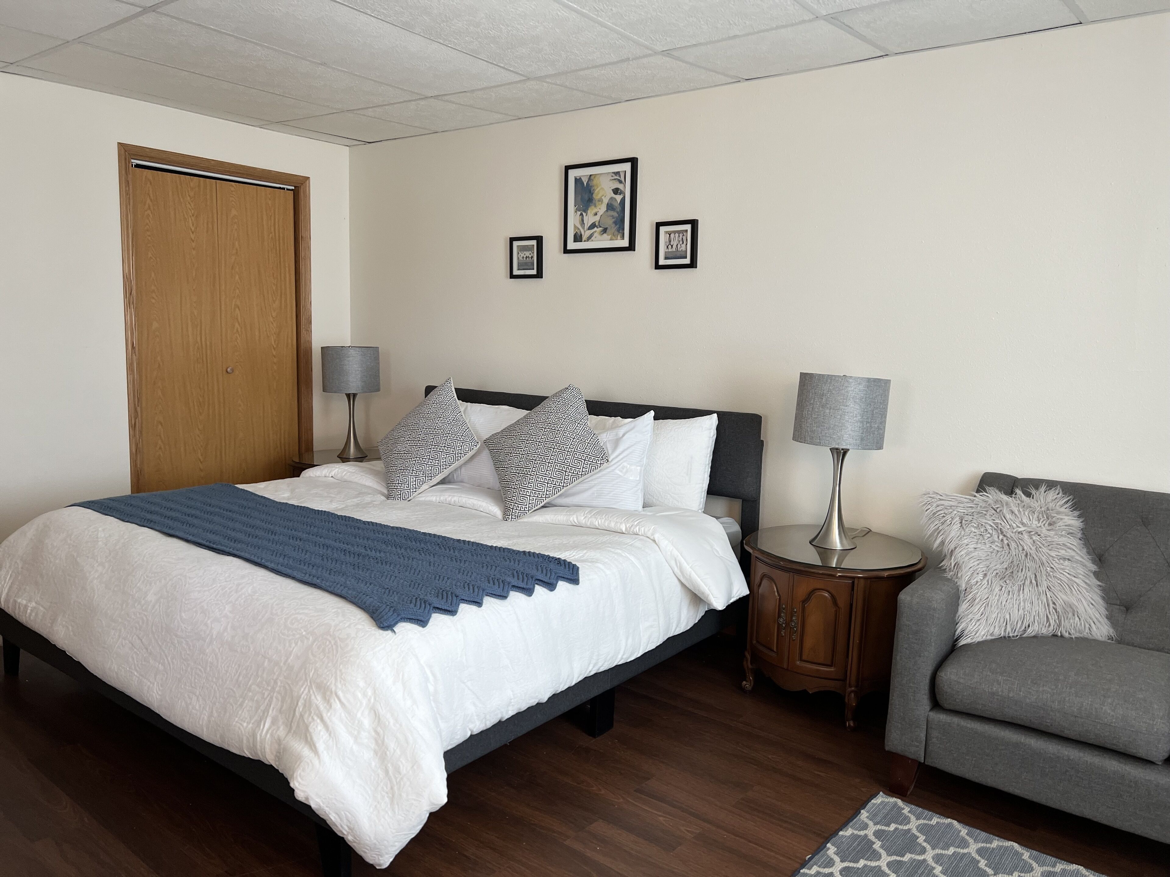 A neatly arranged bedroom with a bed, bedside tables, a chair, and a door.