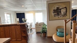 Ein geräumiger Wohnbereich mit Holzboden, eine Küchenzeile mit Holzauszug, ein Esstisch und eine Treppe.