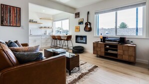 A living room with a brown leather sofa, a glass coffee table, and a wooden entertainment unit with a record player. - Hang Ten at the Studio! Vibe in This Groovy Avila Beach Studio Condo! (Avila Beach)
