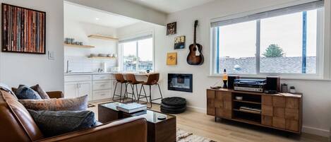 A living room with a brown leather sofa, a glass coffee table, and a wooden entertainment unit with a record player.