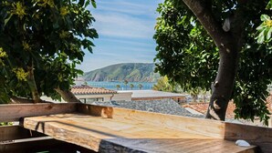 A wooden deck with a view of a coastal area, including a pier and hills. - Hang Ten at the Studio! Vibe in This Groovy Avila Beach Studio Condo! (Avila Beach)
