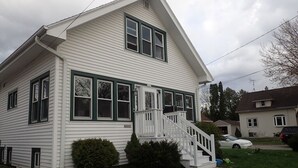 A two-story house with a front porch and a staircase leading to the entrance.