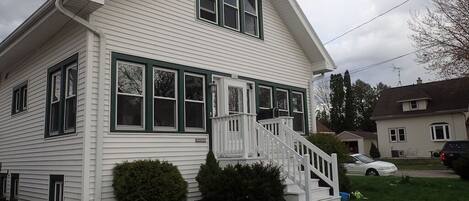 A two-story house with a front porch and a staircase leading to the entrance.