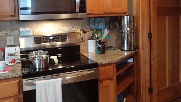 A kitchen with wooden cabinets, a stainless steel microwave, an oven, and a coffee maker.