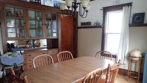 A dining room with a wooden table and chairs, a cabinet with glass doors, and a globe on a stand.