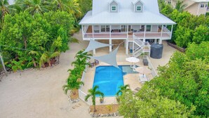 A two-story house with a swimming pool, surrounded by lush greenery and palm trees. - P35 - Spacious 4 bedroom, 3 bath home boasts generous harbor views (Marathon)