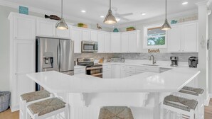 A modern kitchen with white cabinetry, stainless steel appliances, and a central island with bar stools. - P35 - Spacious 4 bedroom, 3 bath home boasts generous harbor views (Marathon)
