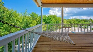 A wooden deck with a hammock, white railings, and a view of lush greenery. - P35 - Spacious 4 bedroom, 3 bath home boasts generous harbor views (Marathon)