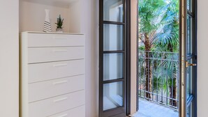 A room with a white dresser, a sliding glass door leading to a balcony with palm trees.