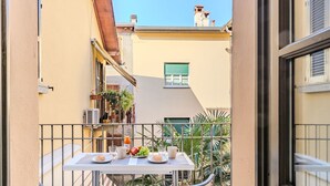 A balcony with a table set for two, chairs, and a small garden area with plants.