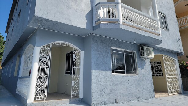 A multi-story building with balconies, decorative railings, and a central entrance with a gate.