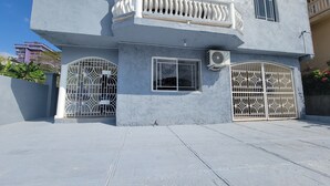 A two-story building with a balcony, barred windows, and an air conditioning unit.