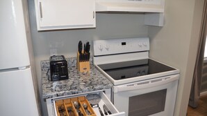 Una cocina compacta con horno integrado, tostadora y organizador de cajones para utensilios.