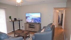 Una sala de estar con un televisor de pantalla plana, un sofá, una mesa de centro y un mueble para televisión.