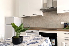 Een moderne keuken met witte kasten, een roestvrijstalen afzuigkap en een potplant op de tafel.