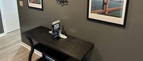 Ein Zimmer mit zwei gerahmten Bildern der Golden Gate Bridge, einem kleinen Tisch mit einem Buch mit dem Titel 'New York' und einem dekorativen Wandkunstwerk.