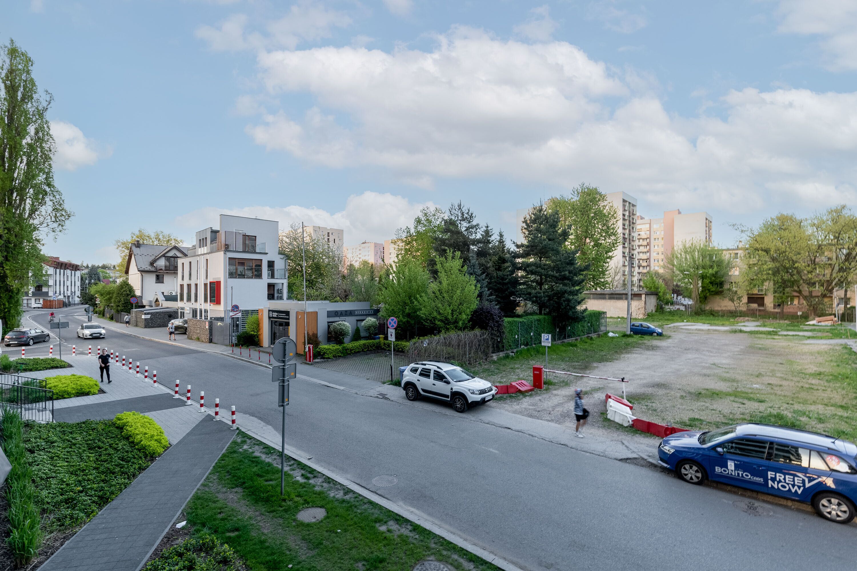 A modern urban street with buildings, cars, and a pedestrian pathway.