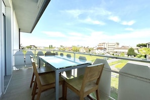 Ein Balkon mit Tisch und Stühlen, mit Blick auf eine Wohngegend mit Häusern und Grünflächen.