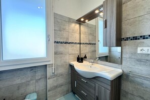 Un baño moderno con un ventanal grande, un lavabo con espejo y un mueble con cajones.