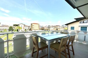 Un balcón con mesa y sillas, con vistas a una zona residencial con edificios y árboles.