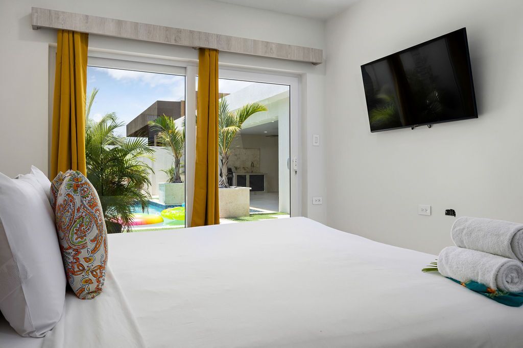 Une chambre d’hôtel avec un lit, une télévision et une vue sur une piscine et un espace extérieur.